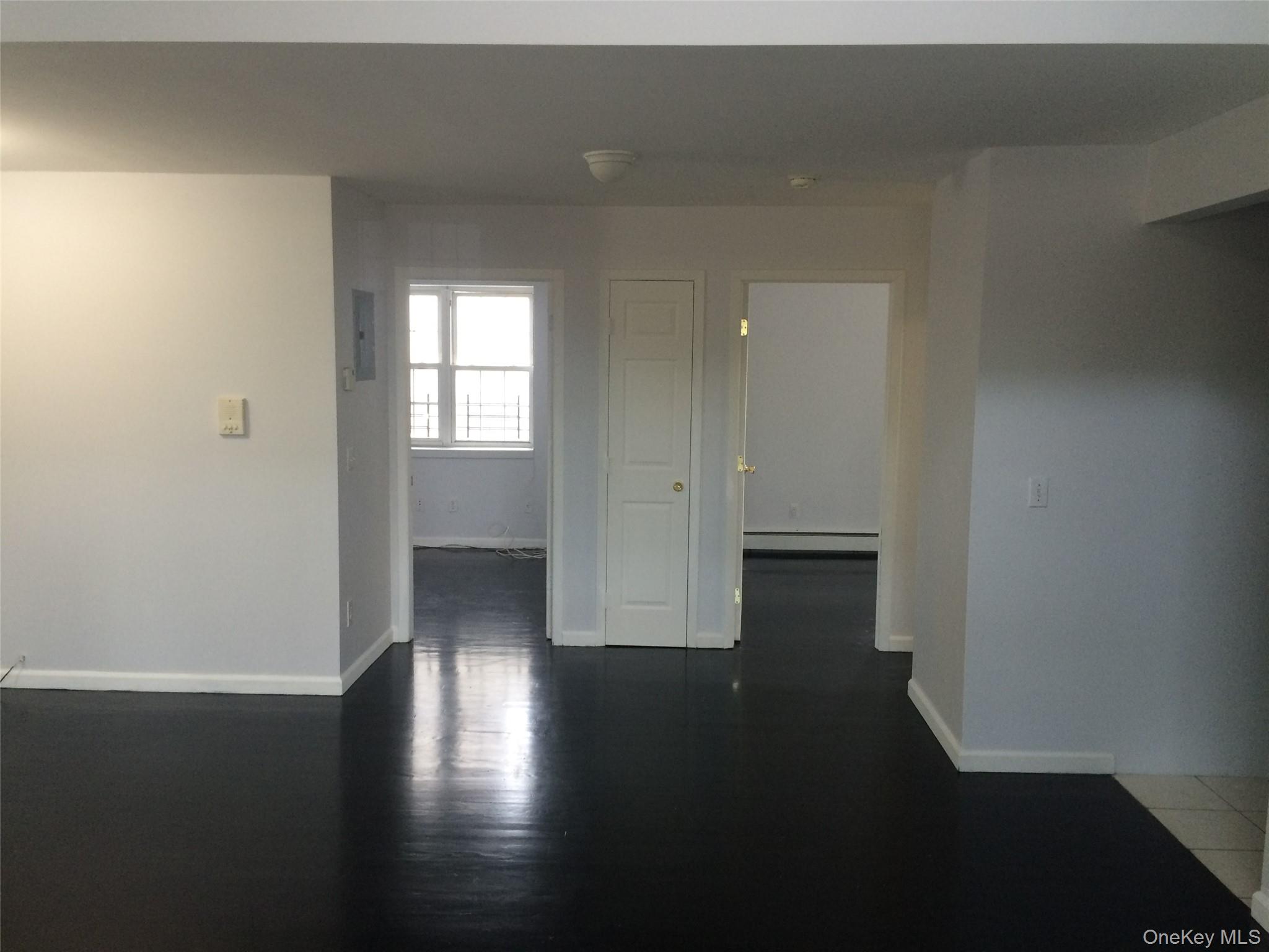 97-56 105th Street, Unit 2 Queens, NY 11416 - Photo 7 of 29 an empty room with wooden floor and windows