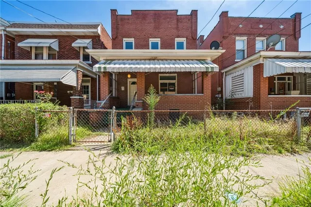 front view of a brick house with a small yard