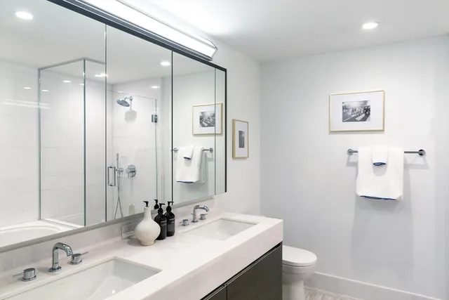 a bathroom with a double vanity sink toilet mirror and shower
