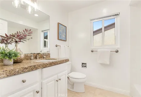 a bathroom with a granite countertop sink a toilet and mirror