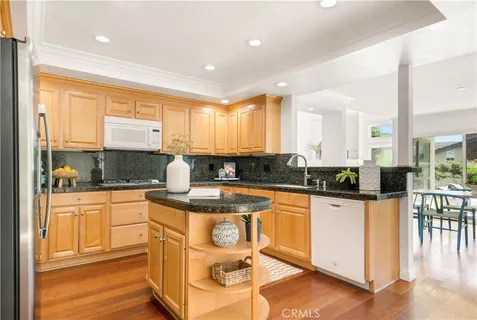 a kitchen with stainless steel appliances granite countertop a stove a sink and white cabinets with wooden floor
