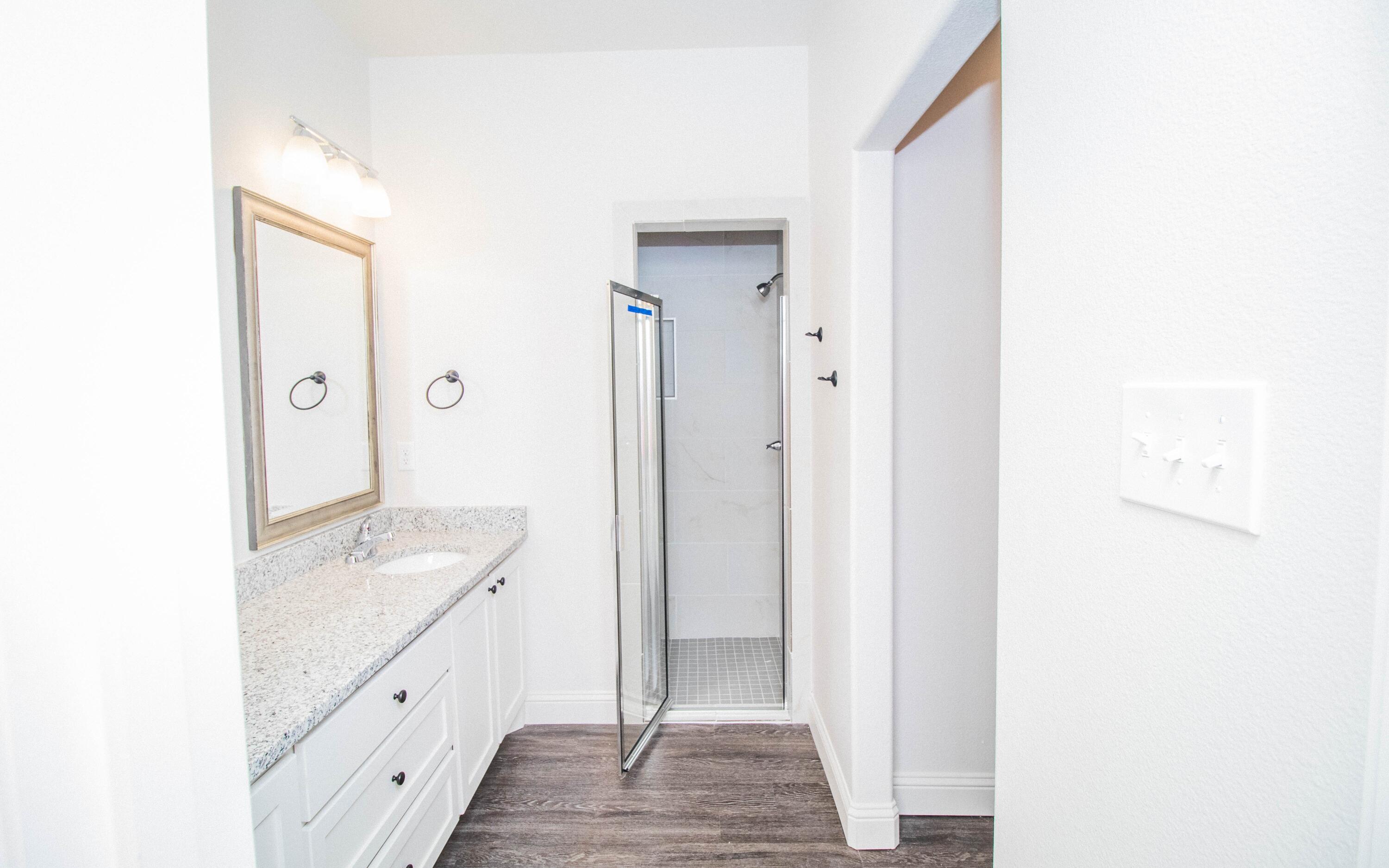 1613 102nd Street Lubbock, TX 79423 - Photo 10 of 18 a spacious bathroom with a granite countertop sink and a mirror