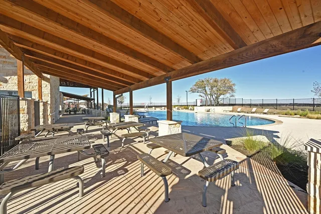 a view of a swimming pool with lawn chairs and potted plants