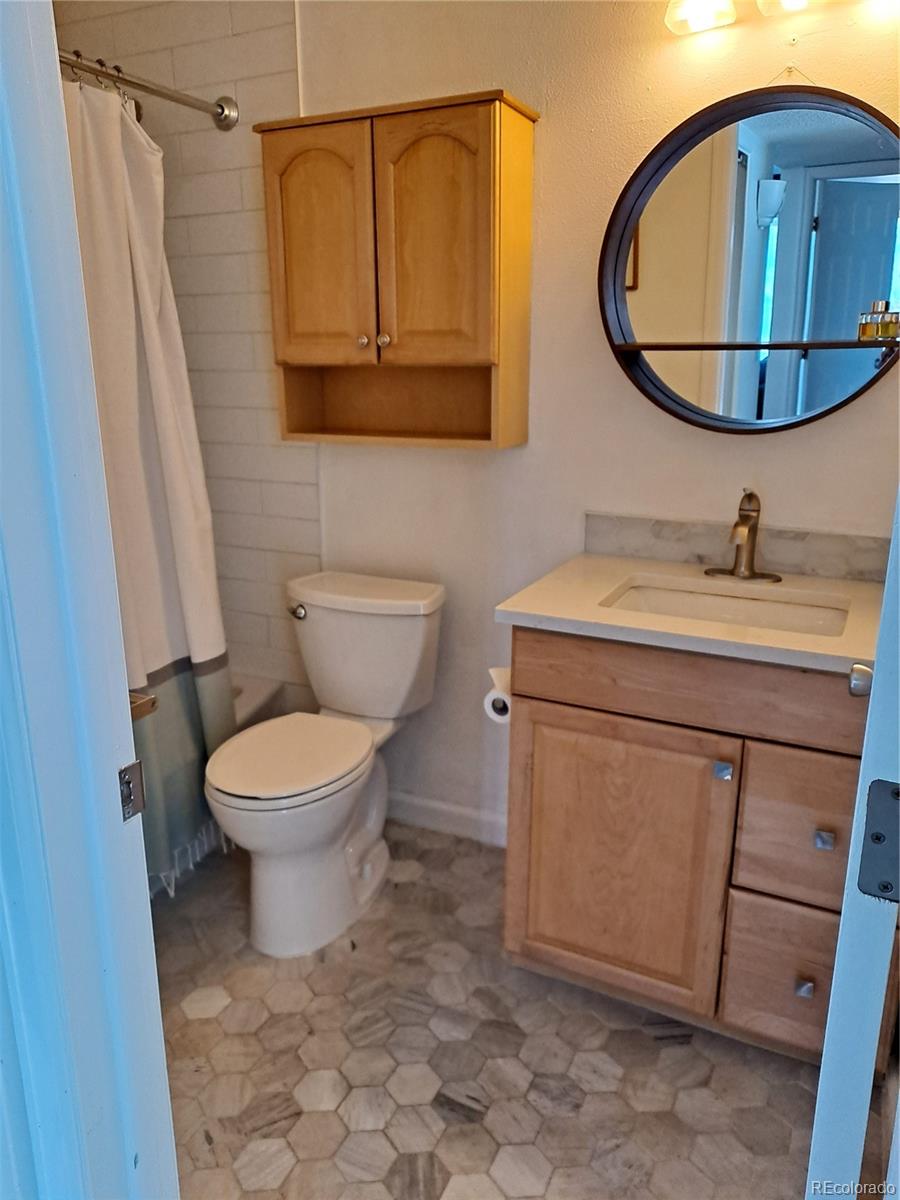 2575 South Syracuse Way, Unit J308 Denver, CO 80231 - Photo 12 of 14 a bathroom with a toilet a sink and a mirror