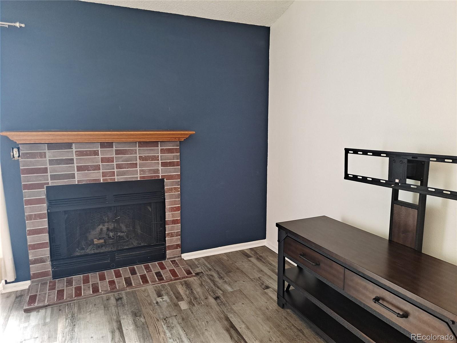 2575 South Syracuse Way, Unit J308 Denver, CO 80231 - Photo 6 of 14 a living room with furniture a fireplace and wooden floor