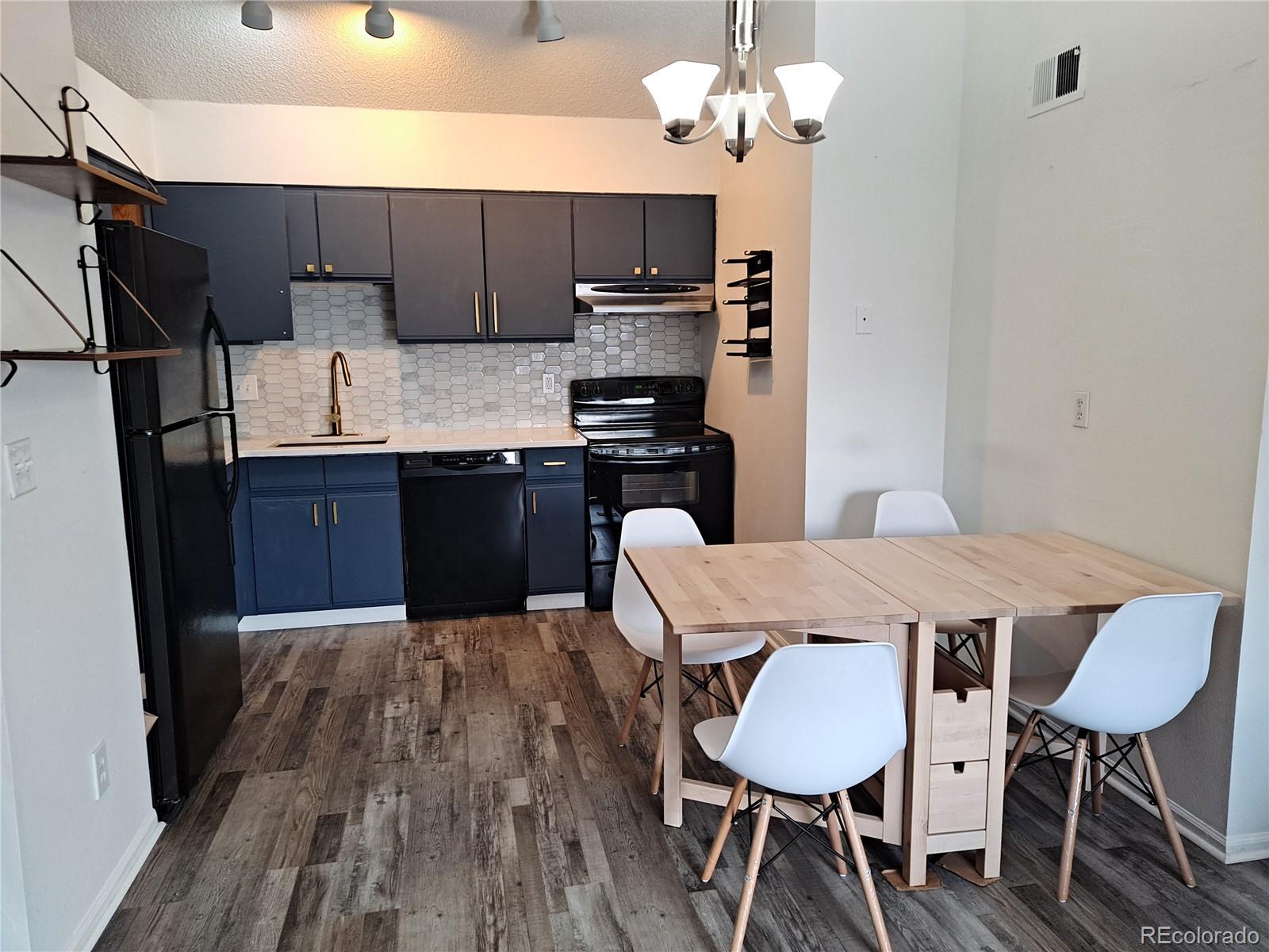 2575 South Syracuse Way, Unit J308 Denver, CO 80231 - Photo 8 of 14 a kitchen with stainless steel appliances granite countertop a sink dishwasher a stove a refrigerator with a dining table and chair