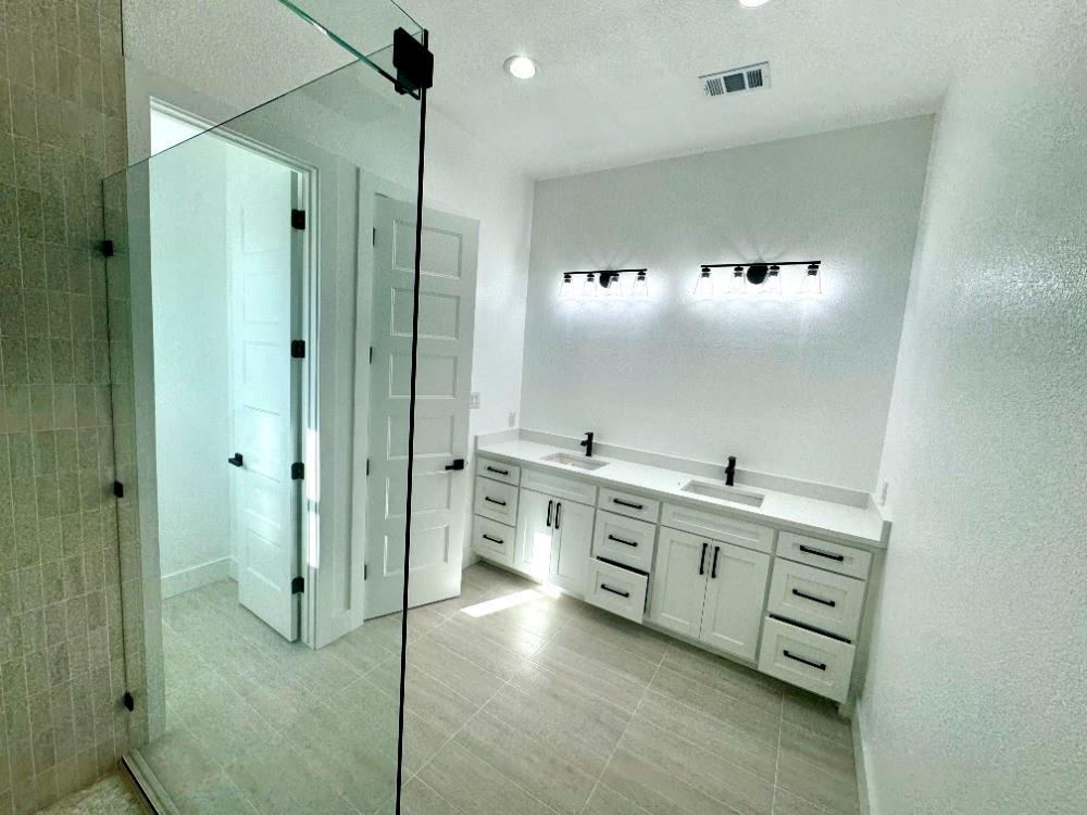 1106 East Sixth Street Springtown, TX 76082 - Photo 15 of 25 a large bathroom with a double vanity sink a mirror and shower