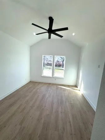 an empty room with wooden floor fan and windows