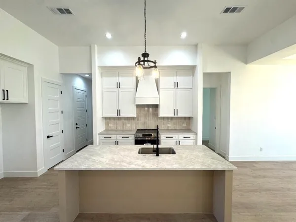 a kitchen with stainless steel appliances kitchen island granite countertop a sink a stove and a refrigerator