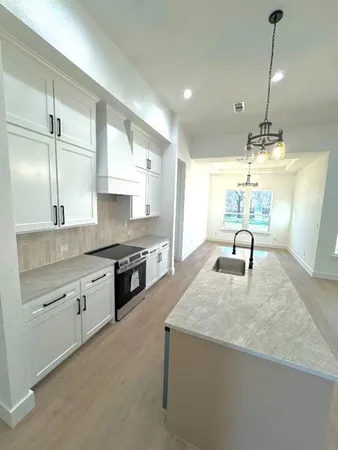 a kitchen with stainless steel appliances granite countertop a sink a stove and a wooden floors