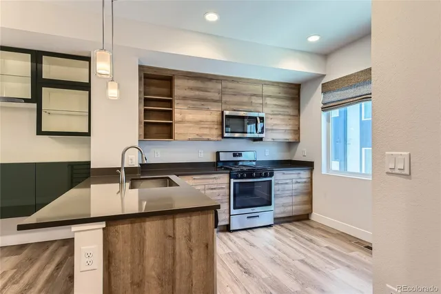 a kitchen with stainless steel appliances granite countertop a sink stove microwave and refrigerator