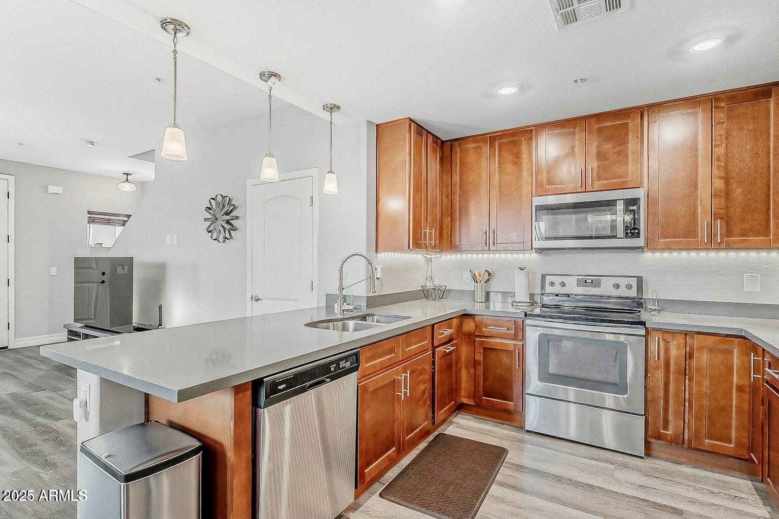 2821 South Skyline Drive, Unit 141 Mesa, AZ 85212 - Photo 11 of 68 a kitchen with stainless steel appliances granite countertop a sink a stove and a wooden floors