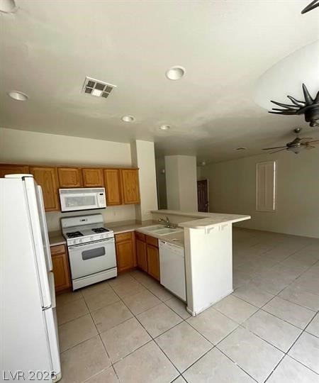 677 Principle Point Avenue Henderson, NV 89012 - Photo 6 of 40 Kitchen featuring white appliances, light countertops, a peninsula, light tile patterned floors, and wood finish cabinets