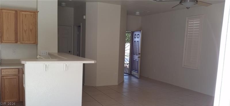 677 Principle Point Avenue Henderson, NV 89012 - Photo 7 of 40 Kitchen with light countertops, light tile patterned floors, a ceiling fan, a peninsula, and wood finish cabinetry