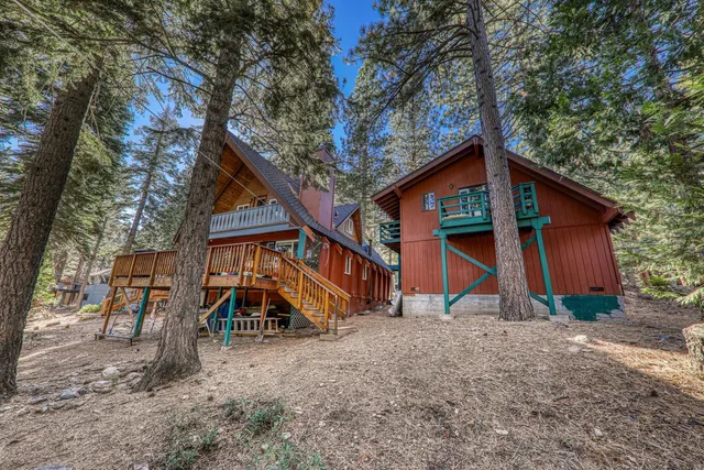 a view of wooden house with a yard and sitting area