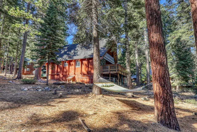 a view of a house with large tree and wooden fence