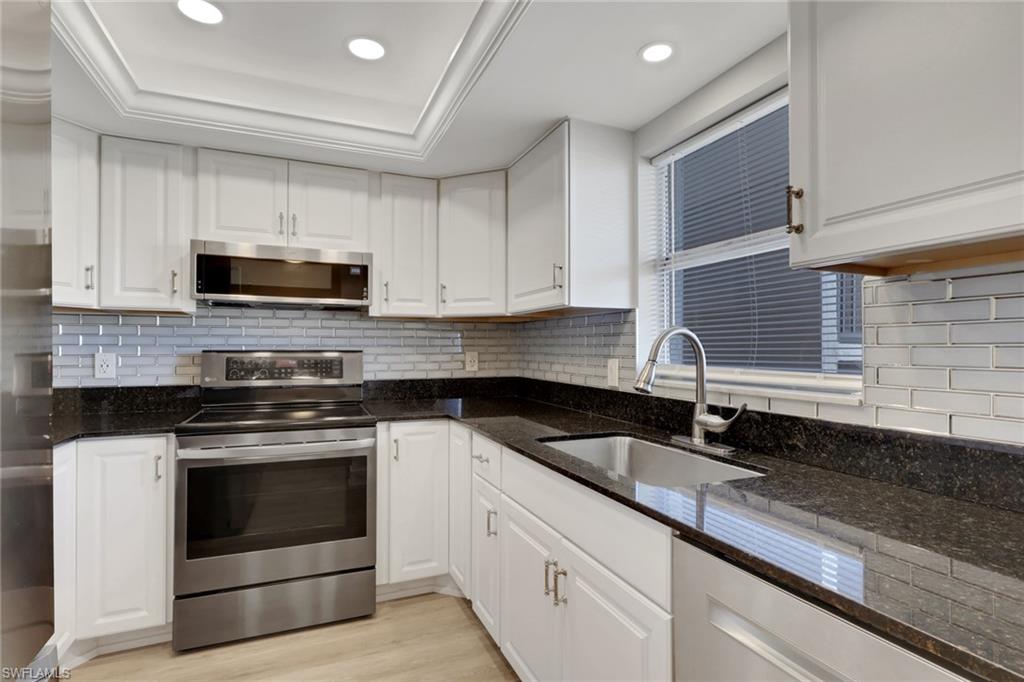 a kitchen with sink a microwave a stove and cabinets