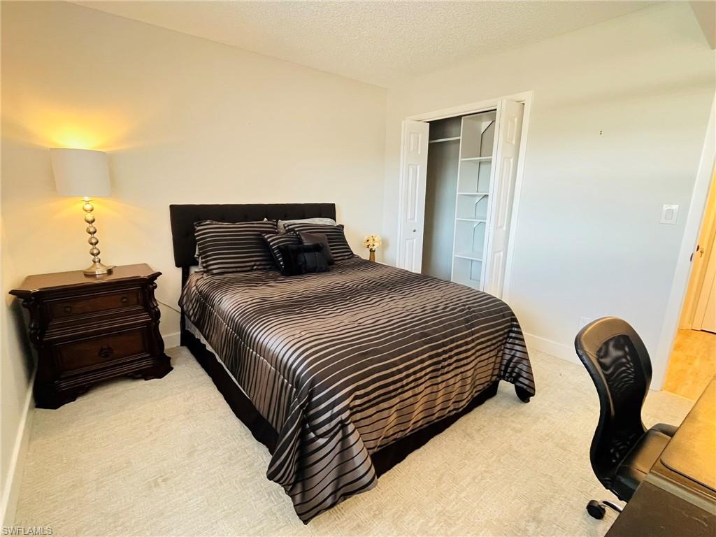5499 Rattlesnake Hamm Road, Unit 2 Naples, FL 34113 - Photo 12 of 23 Bedroom with light carpet, a textured ceiling, and a closet