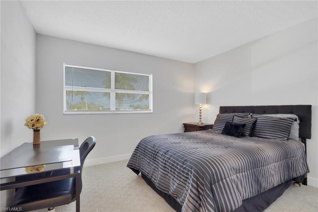 5499 Rattlesnake Hamm Road, Unit 2 Naples, FL 34113 - Photo 12 of 34 a bedroom with a bed a table and a window
