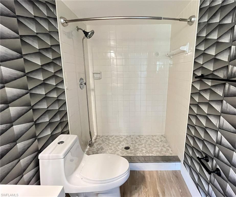 5499 Rattlesnake Hamm Road, Unit 2 Naples, FL 34113 - Photo 17 of 23 Bathroom with a shower stall, wood finished floors, and tile walls