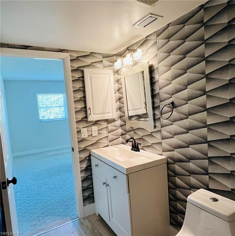 5499 Rattlesnake Hamm Road, Unit 2 Naples, FL 34113 - Photo 18 of 23 Half bathroom featuring vanity and light carpet