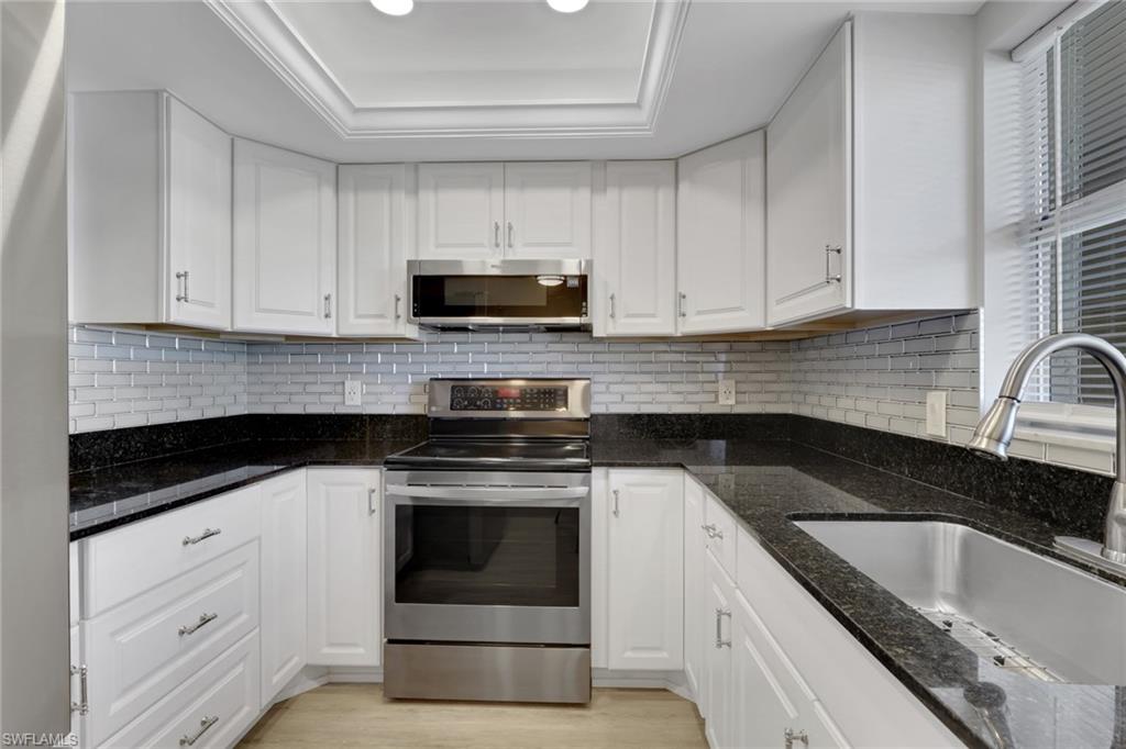 5499 Rattlesnake Hamm Road, Unit 2 Naples, FL 34113 - Photo 2 of 34 a kitchen with granite countertop white cabinets sink and stainless steel appliances