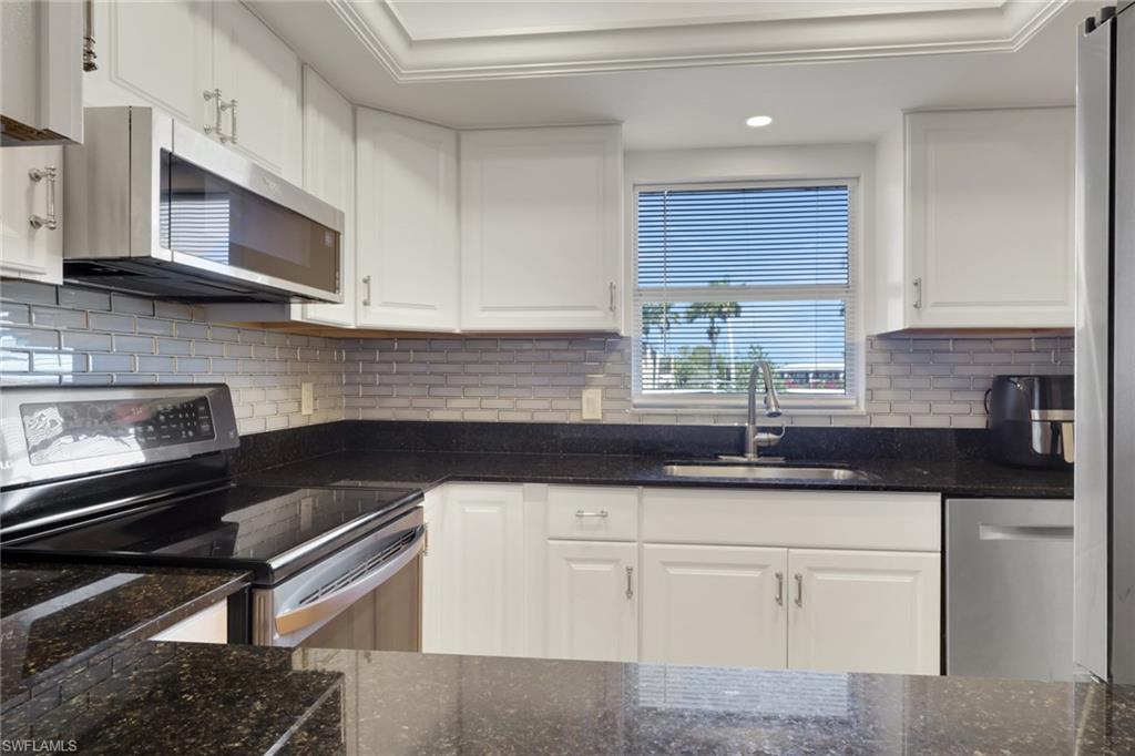 5499 Rattlesnake Hamm Road, Unit 2 Naples, FL 34113 - Photo 3 of 34 a kitchen with granite countertop white cabinets and a stove top oven