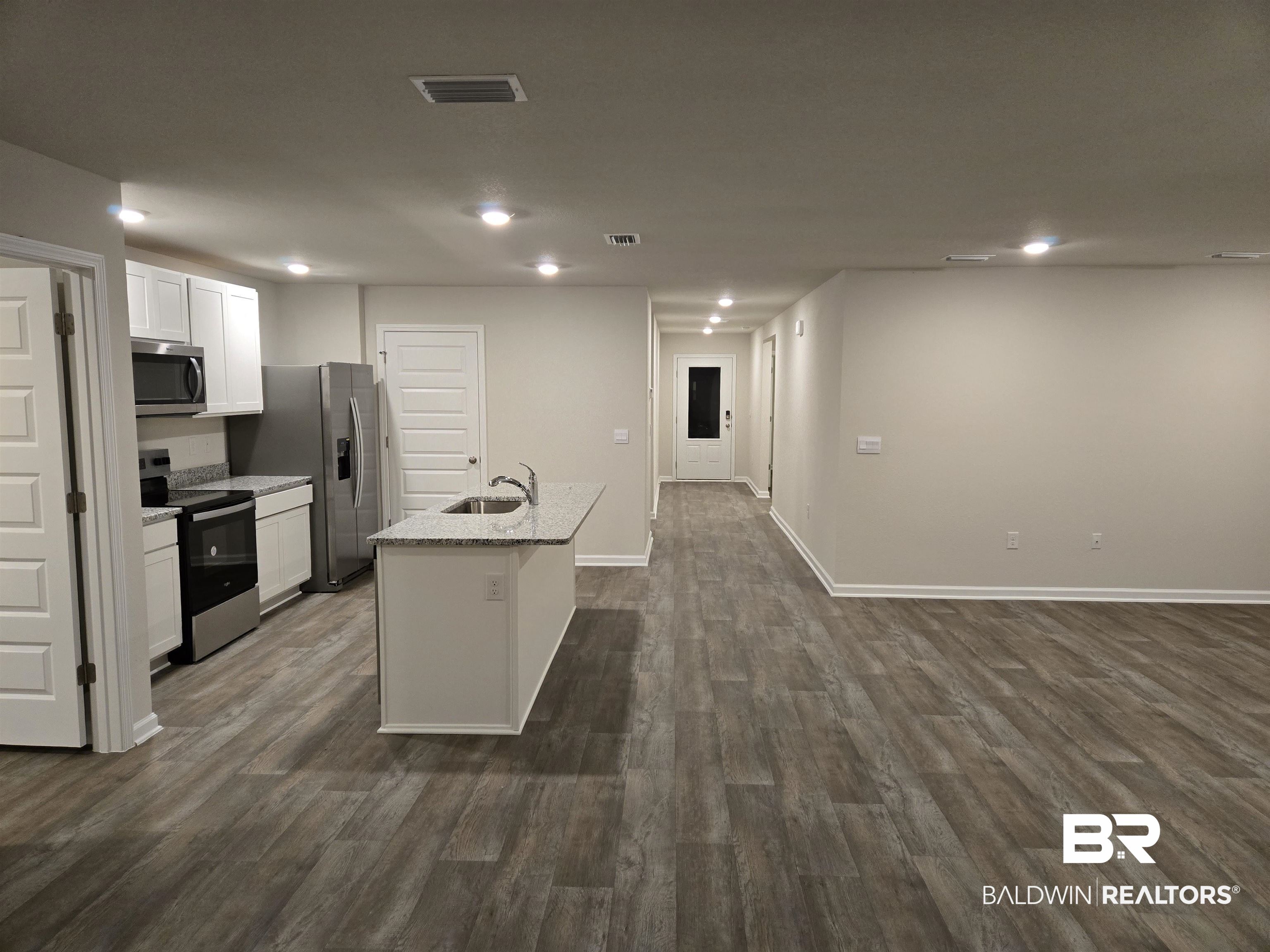24194 Veranda Circle Elberta, AL 36530 - Photo 21 of 31 Kitchen featuring white cabinetry, sink, stainless steel appliances, dark hardwood / wood-style flooring, and a kitchen island with sink