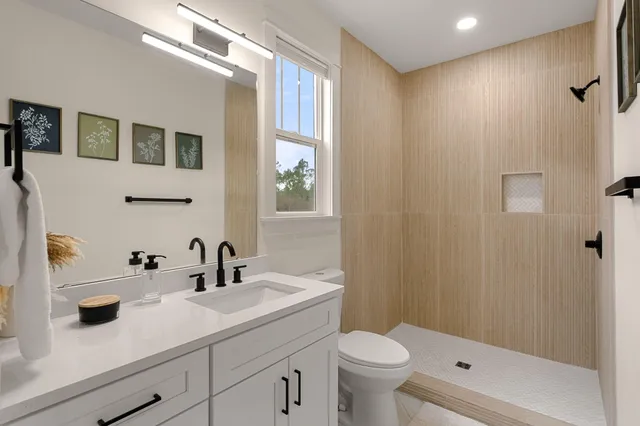 a bathroom with a sink a toilet a mirror and shower