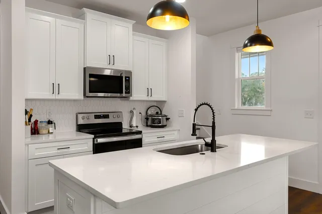 a kitchen with stainless steel appliances a stove a sink a microwave and cabinets