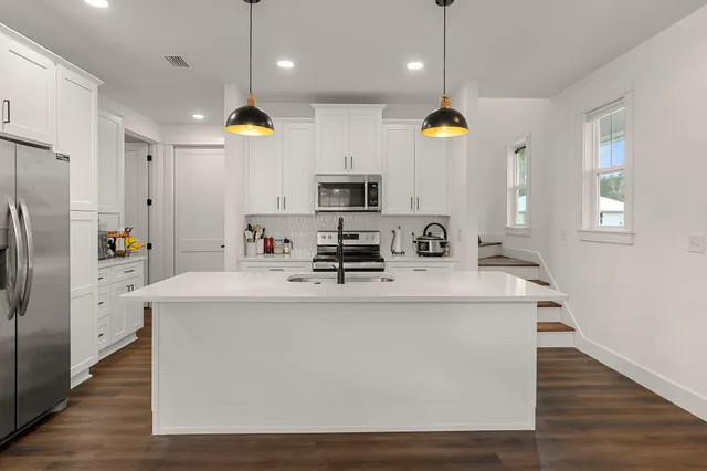 a kitchen with kitchen island stainless steel appliances a sink a stove and refrigerator