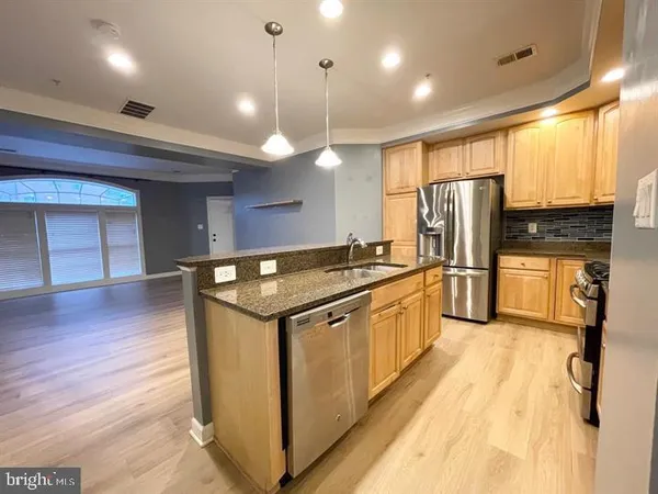 a kitchen with stainless steel appliances granite countertop a refrigerator a oven and a stove with wooden floor