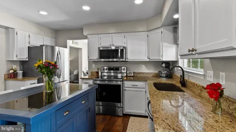 a kitchen with granite countertop a sink stove and refrigerator