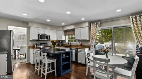 a kitchen with stainless steel appliances granite countertop a stove top oven a sink dishwasher a dining table and chairs with wooden floor