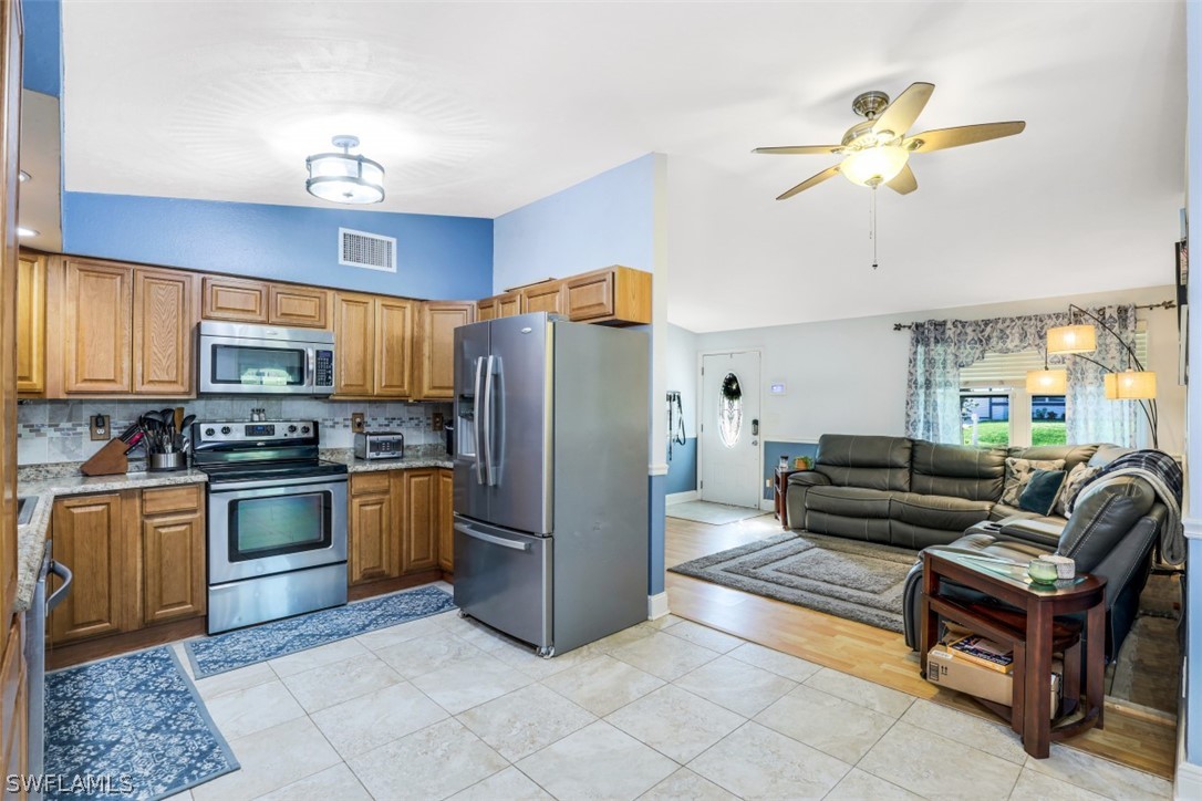 701 East 14th Street Lehigh Acres, FL 33972 - Photo 5 of 31 a kitchen with stainless steel appliances granite countertop a refrigerator a stove a sink dishwasher a dining table and chairs with wooden floor