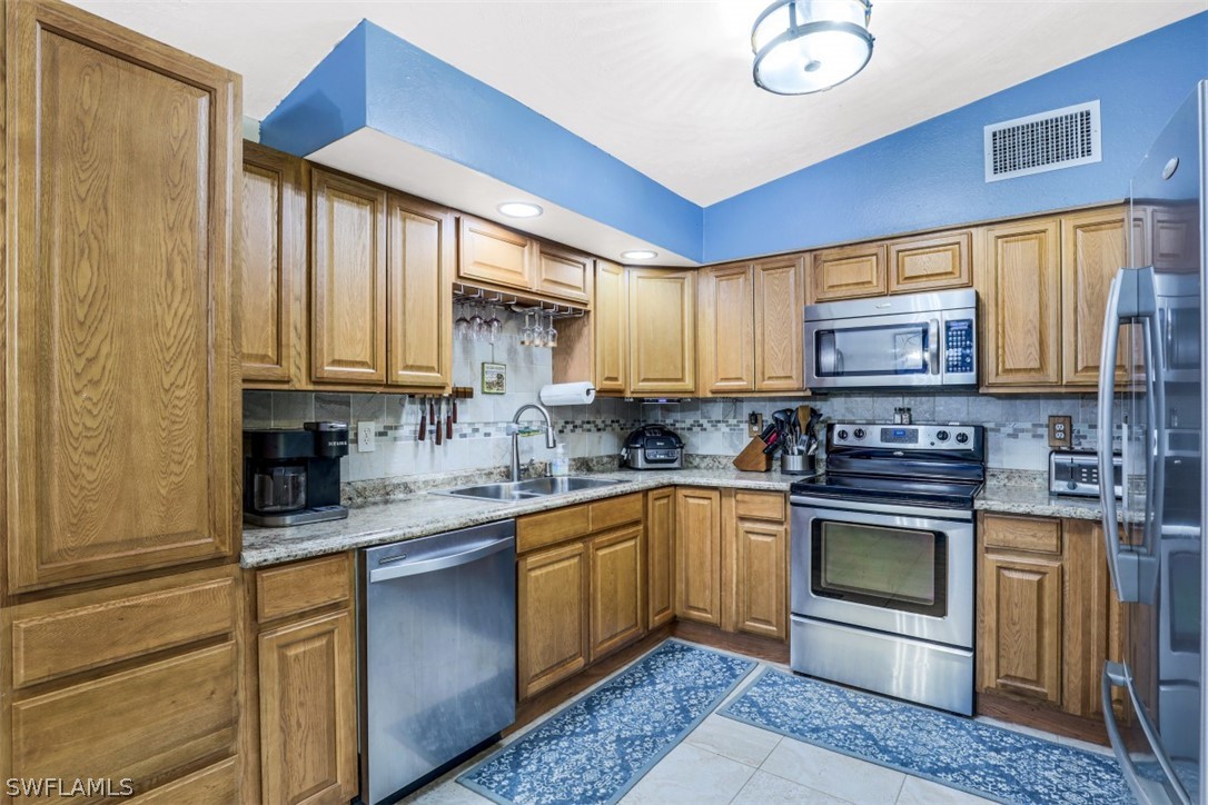 701 East 14th Street Lehigh Acres, FL 33972 - Photo 6 of 31 a kitchen with stainless steel appliances granite countertop a stove a sink dishwasher and a microwave oven