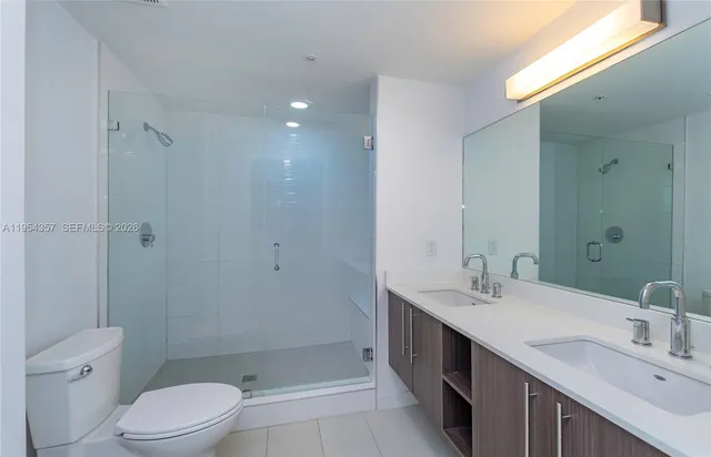 a bathroom with a double vanity sink toilet and shower