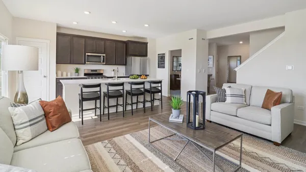 a living room with furniture a wooden floor and kitchen view
