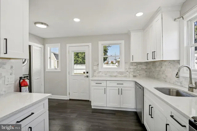 a kitchen with white cabinets and sink