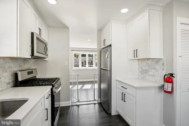 a kitchen with stainless steel appliances granite countertop a refrigerator sink and white cabinets