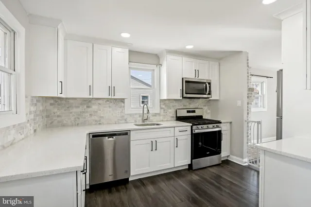 a kitchen with granite countertop white cabinets and stainless steel appliances