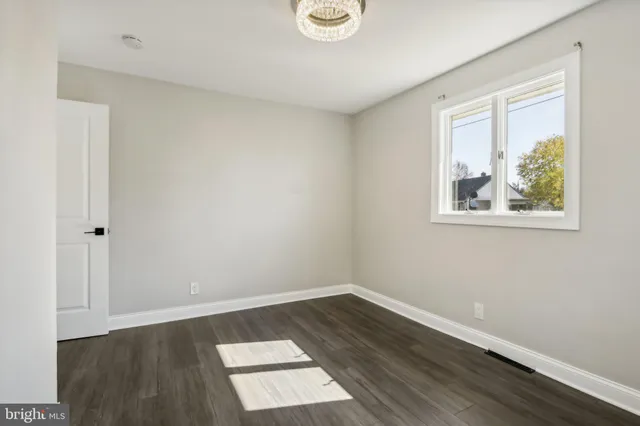 an empty room with wooden floor and window