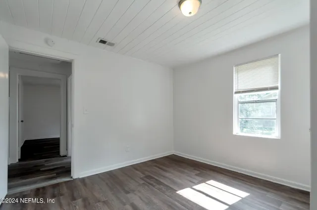 an empty room with wooden floor cabinet and windows