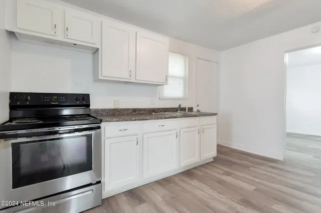 a kitchen with granite countertop white cabinets and appliances
