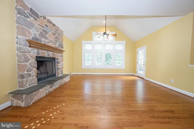 a view of an empty room with wooden floor fireplace and a window