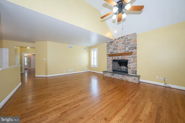 a view of an empty room with wooden floor and a fireplace