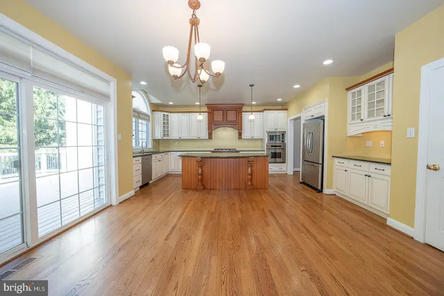 a large kitchen with kitchen island a large window and wooden floor
