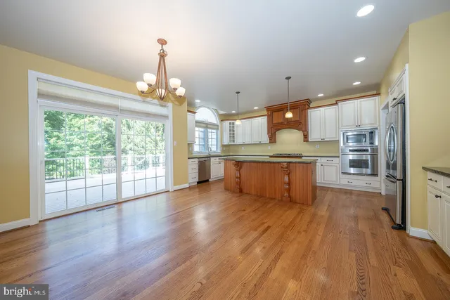 a large kitchen with stainless steel appliances granite countertop a large window and a refrigerator