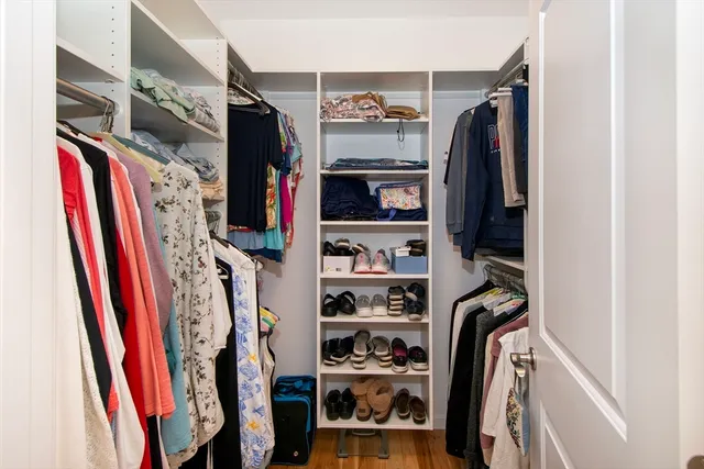 a view of walk in closet with clothes and shoes