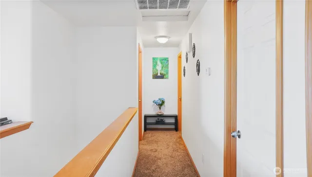 a view of a hallway with wooden floor and a bathroom